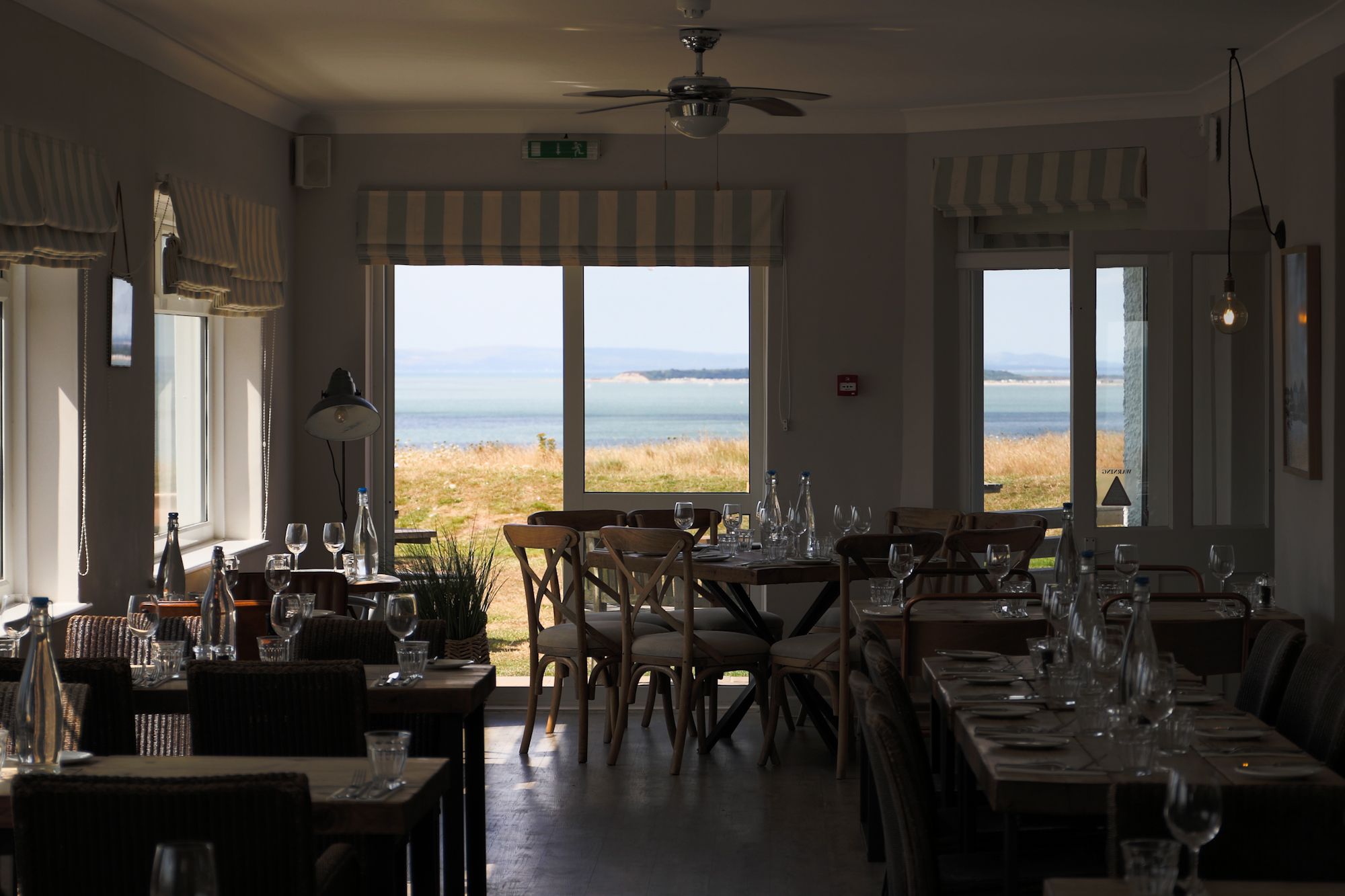 The restaurant at The Cliff House, tables laid, with the sea through the windows